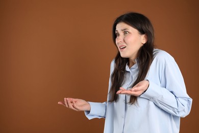 Photo of Portrait of shocked woman on brown background, space for text