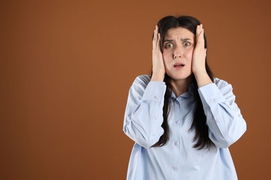 Photo of Portrait of shocked woman on brown background, space for text