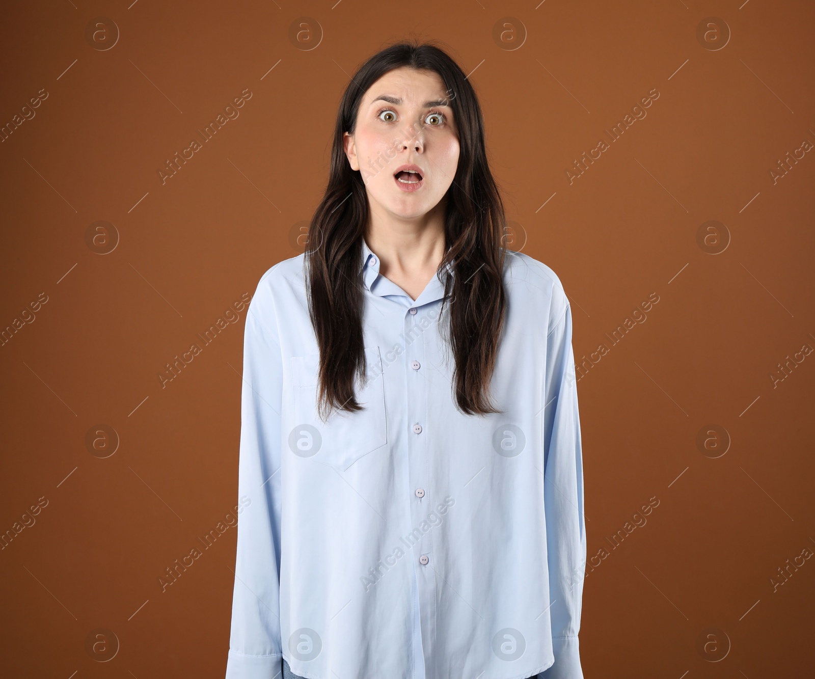 Portrait of shocked woman on brown background Photo of Portrait of shocked woman on brown background
