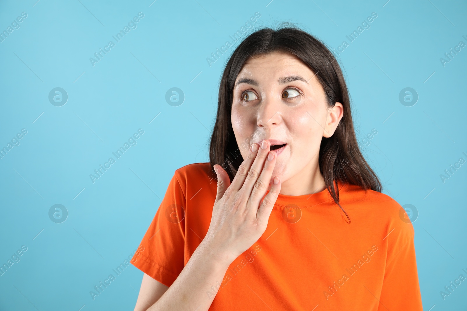 Portrait of surprised woman on light blue background, space for text Photo of Portrait of surprised woman on light blue background, space for text