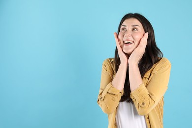 Photo of Portrait of surprised woman on light blue background, space for text