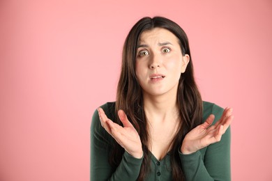 Photo of Portrait of confused woman on pink background, space for text