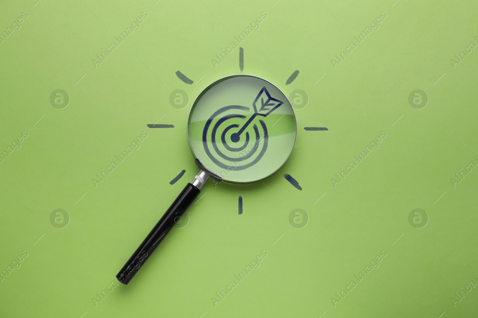 Magnifying glass over target with arrow on green background, top view Image of Magnifying glass over target with arrow on green background, top view