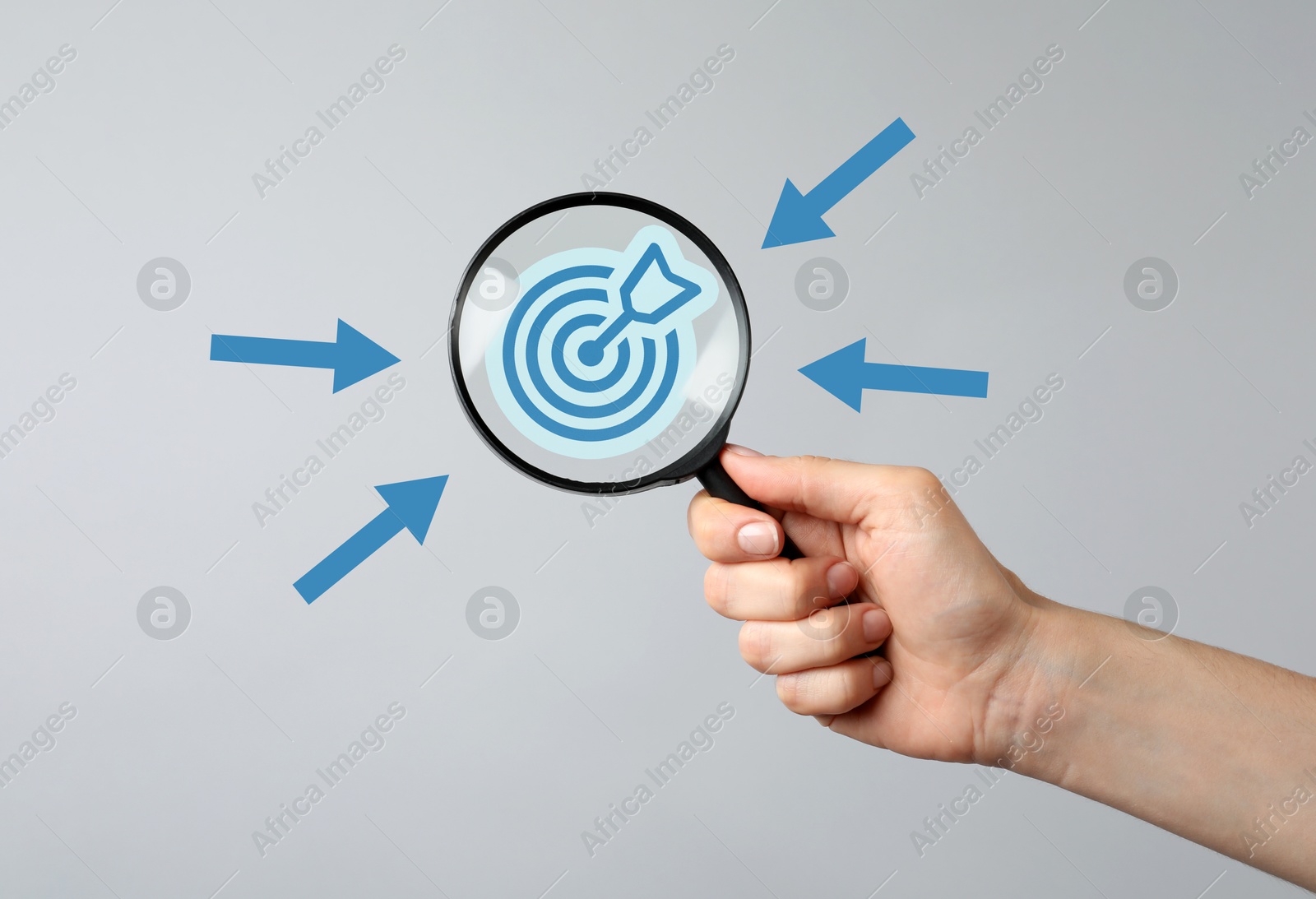 Woman holding magnifying glass with target inside against grey background, closeup. Arrows pointing at magnifier Image of Woman holding magnifying glass with target inside against grey background, closeup. Arrows pointing at magnifier