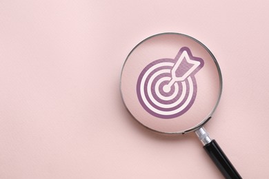 Image of Magnifying glass over target with arrow on pink background, top view