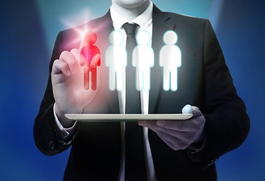 Image of Dismissal. Businessman choosing human figure on virtual screen above tablet computer against dark blue background, closeup