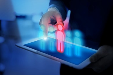 Image of Dismissal. Businessman choosing human figure on virtual screen above tablet computer indoors, closeup