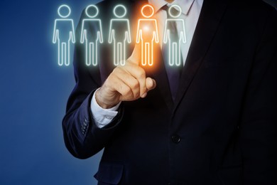 Image of Dismissal. Businessman choosing human figure on virtual screen against dark blue background, closeup