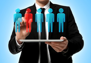 Image of Dismissal. Businessman choosing human figure on virtual screen above tablet computer against light blue background, closeup