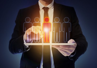 Image of Dismissal. Businessman choosing human figure on virtual screen above tablet computer against dark background, closeup