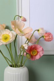 Photo of Beautiful poppy flowers in vase near green wall, closeup