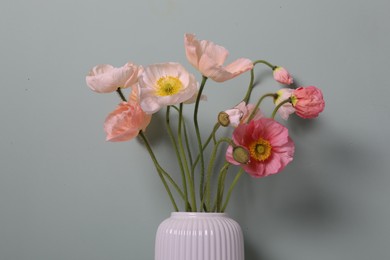 Photo of Beautiful poppy flowers in vase on grey background, closeup