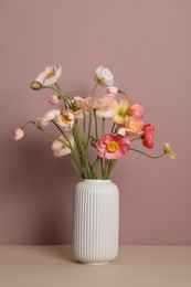 Photo of Beautiful poppy flowers in vase on beige table against pink background
