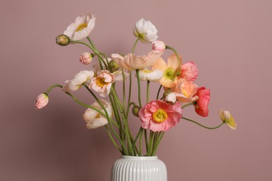 Photo of Beautiful poppy flowers in vase on pink background, closeup