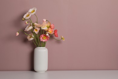 Photo of Beautiful poppy flowers in vase on white table against pink background. Space for text