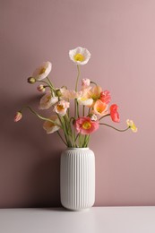 Photo of Beautiful poppy flowers in vase on white table against pink background