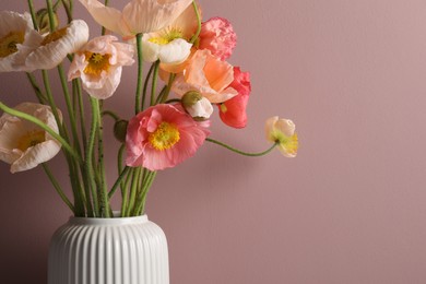 Photo of Beautiful poppy flowers in vase on pink background, closeup. Space for text