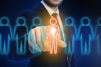 Image of Dismissal. Businessman choosing human figure on virtual screen against dark blue background, closeup
