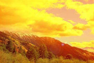 Image of Orange sky with clouds above mountains during hot summer weather