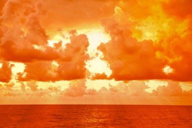 Image of Orange sky with clouds above sea during hot summer weather