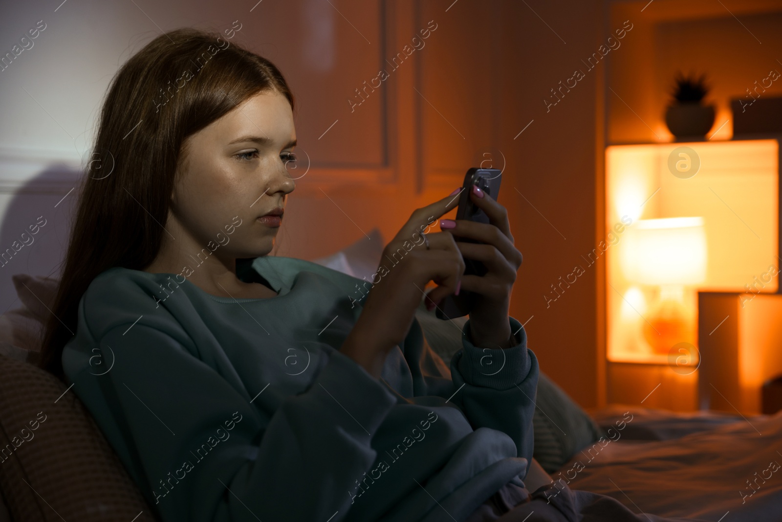 Beautiful teenage girl using smartphone on bed at home Photo of Beautiful teenage girl using smartphone on bed at home