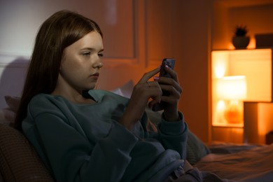 Photo of Beautiful teenage girl using smartphone on bed at home