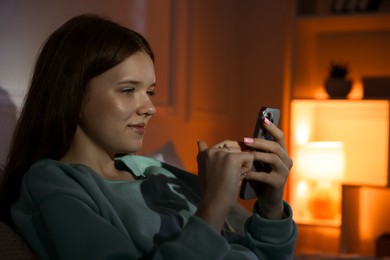 Photo of Beautiful teenage girl using smartphone at home