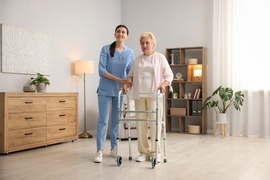 Photo of Nurse assisting senior woman with walking frame indoors. Home health care service