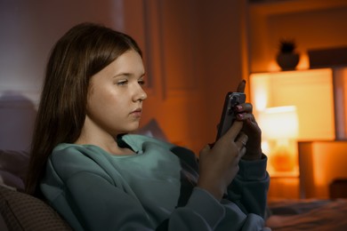 Photo of Beautiful teenage girl using smartphone at home