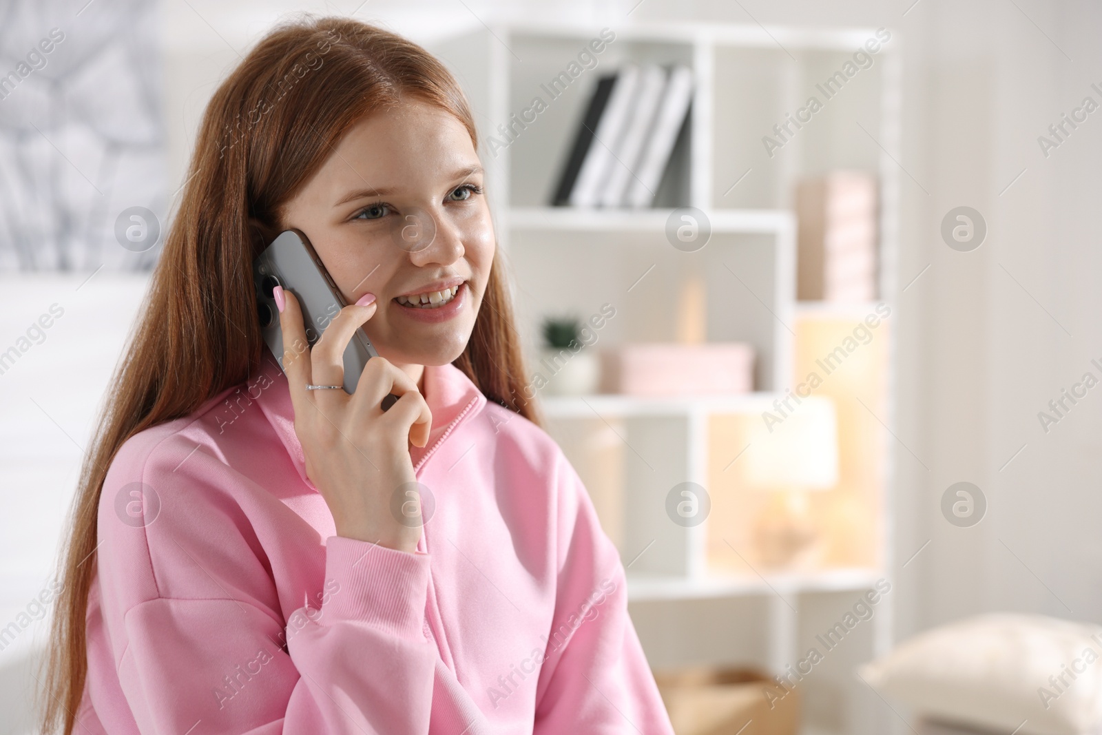 Smiling teenage girl talking by smartphone at home. Space for text Photo of Smiling teenage girl talking by smartphone at home. Space for text