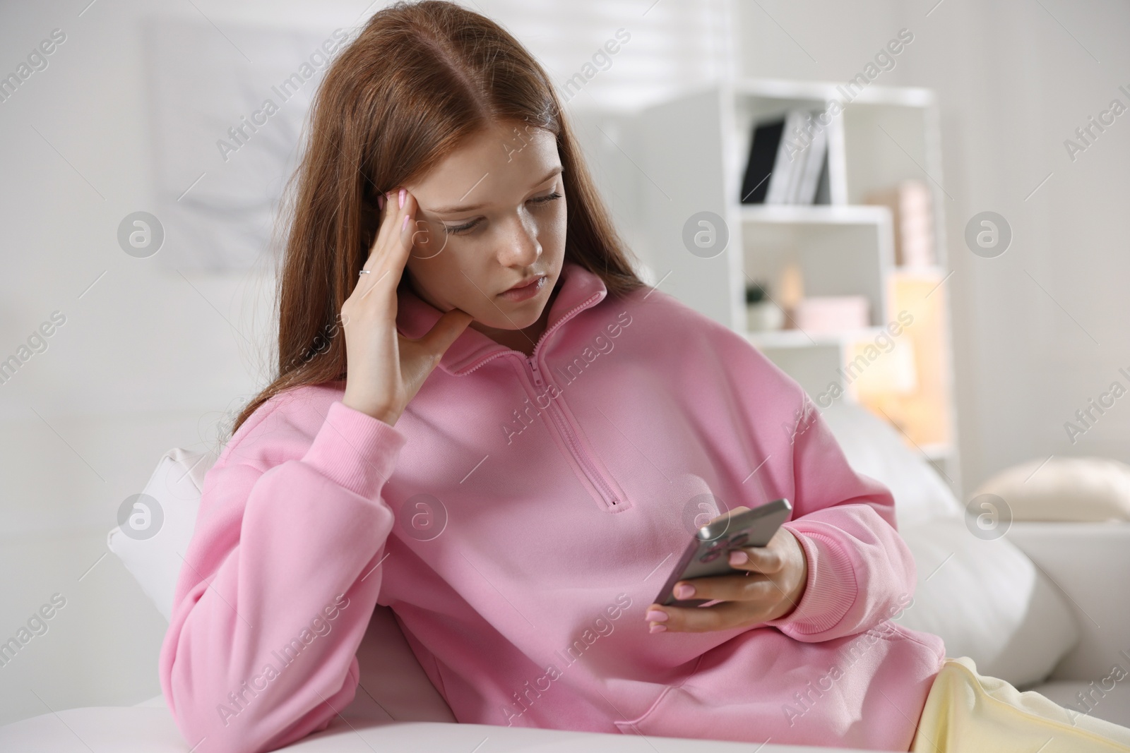Beautiful teenage girl using smartphone on sofa at home Photo of Beautiful teenage girl using smartphone on sofa at home
