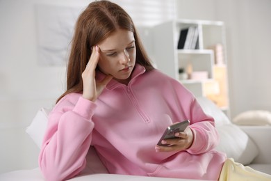 Photo of Beautiful teenage girl using smartphone on sofa at home