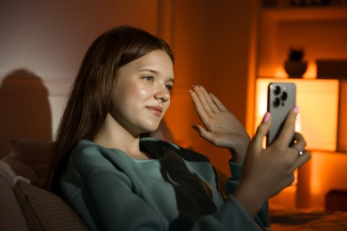 Photo of Beautiful teenage girl having videocall by smartphone at home