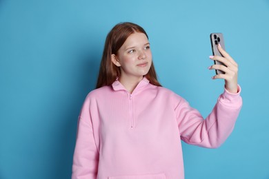 Photo of Beautiful teenage girl with smartphone on light blue background