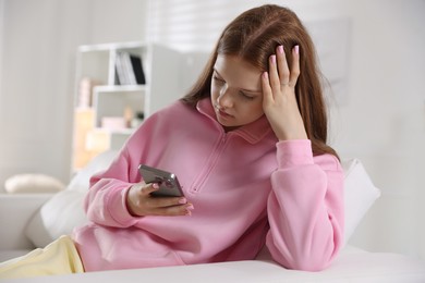 Photo of Beautiful teenage girl using smartphone on sofa at home