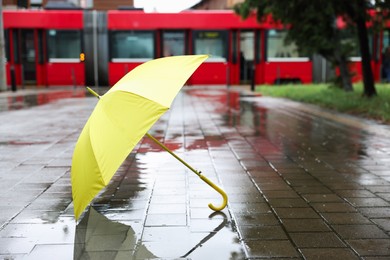 Photo of Yellow umbrella on wet asphalt outdoors, space for text