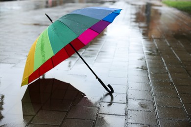 Photo of Colorful umbrella on wet asphalt outdoors, space for text