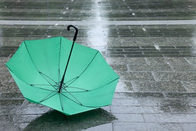 Photo of Green umbrella on wet asphalt outdoors, space for text