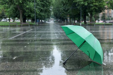 Photo of Green umbrella under heavy rain outdoors, space for text