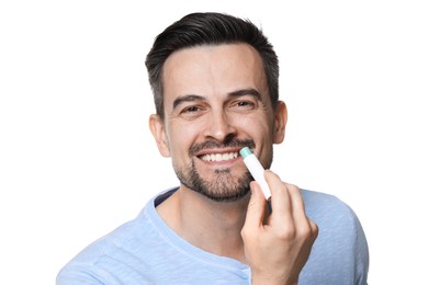 Photo of Smiling man applying lip balm onto his lips on white background