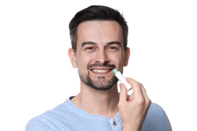 Photo of Smiling man applying lip balm onto his lips on white background