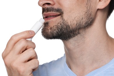 Photo of Smiling man applying lip balm onto his lips on white background, closeup