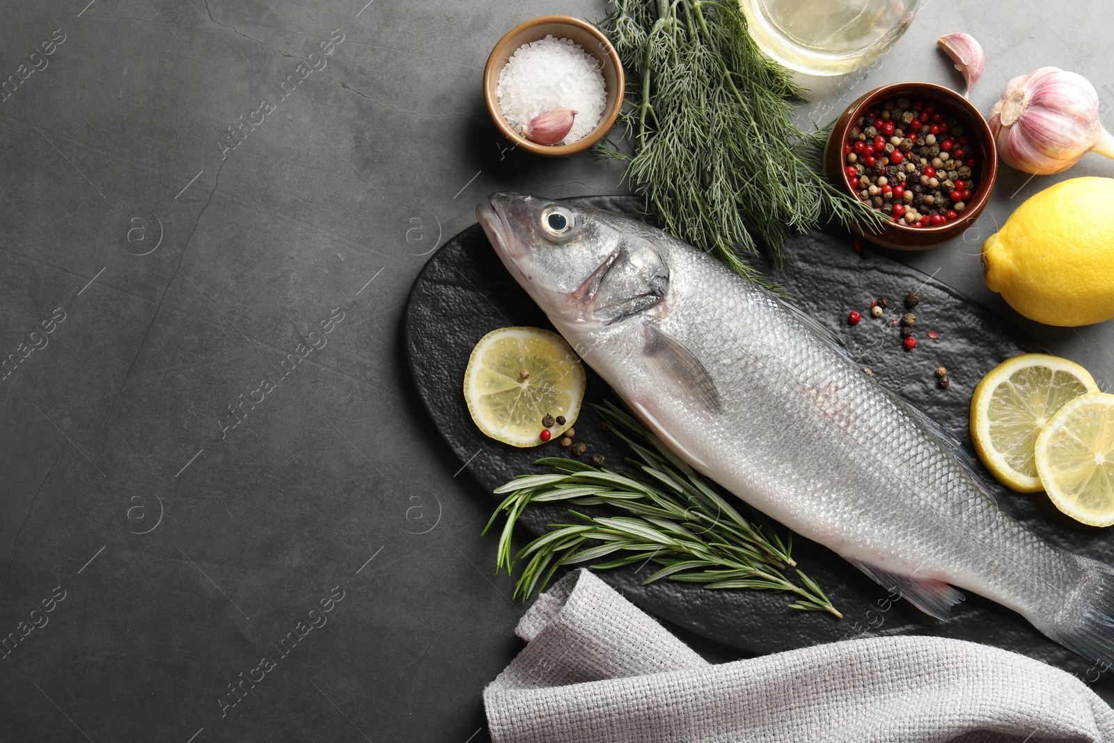 Fresh raw seabass fish with spices on grey table, flat lay and space for text. Seafood delicacies Photo of Fresh raw seabass fish with spices on grey table, flat lay and space for text. Seafood delicacies