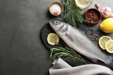 Photo of Fresh raw seabass fish with spices on grey table, flat lay and space for text. Seafood delicacies