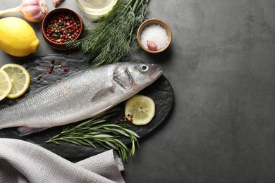 Photo of Fresh raw seabass fish with spices on grey table, flat lay and space for text. Seafood delicacies