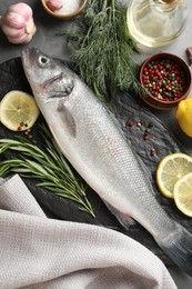 Photo of Fresh raw seabass with spices on grey table, flat lay. Fish and seafood delicacies