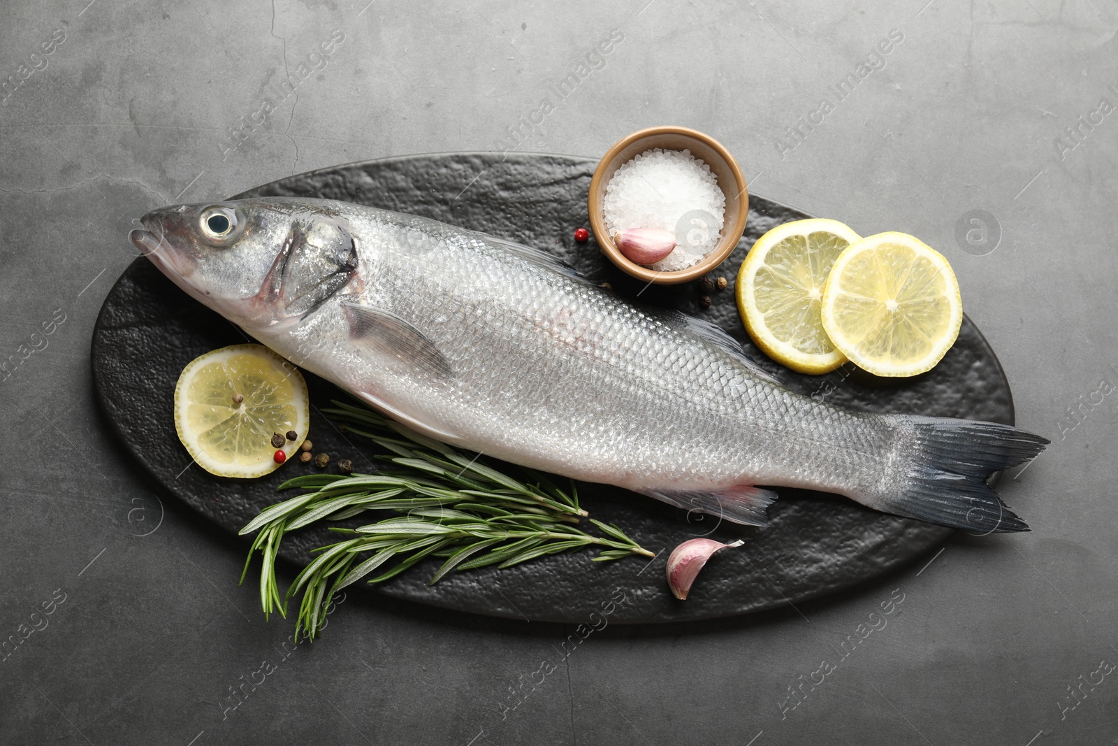 Fresh raw seabass with spices on grey table, top view. Fish and seafood delicacies Photo of Fresh raw seabass with spices on grey table, top view. Fish and seafood delicacies