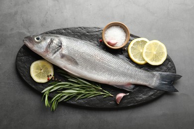 Photo of Fresh raw seabass with spices on grey table, top view. Fish and seafood delicacies