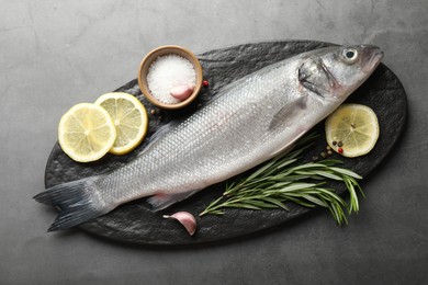 Photo of Fresh raw seabass with spices on grey table, top view. Fish and seafood delicacies