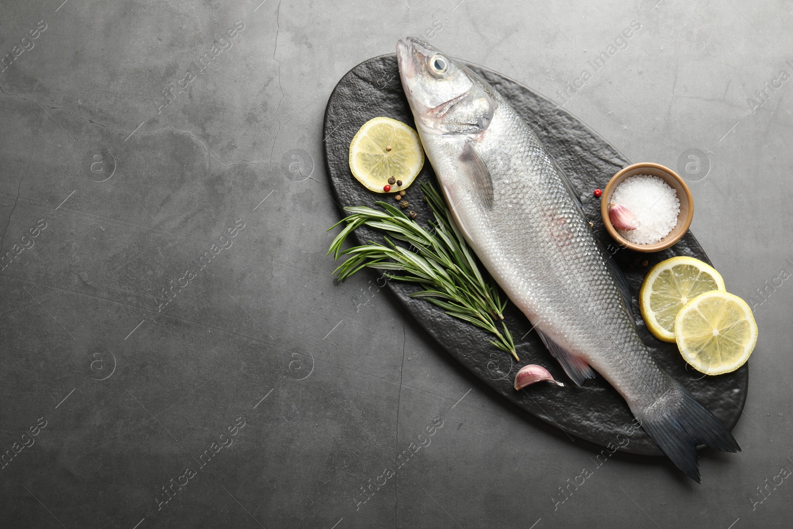 Fresh raw seabass fish with spices on grey table, top view and space for text. Seafood delicacies Photo of Fresh raw seabass fish with spices on grey table, top view and space for text. Seafood delicacies
